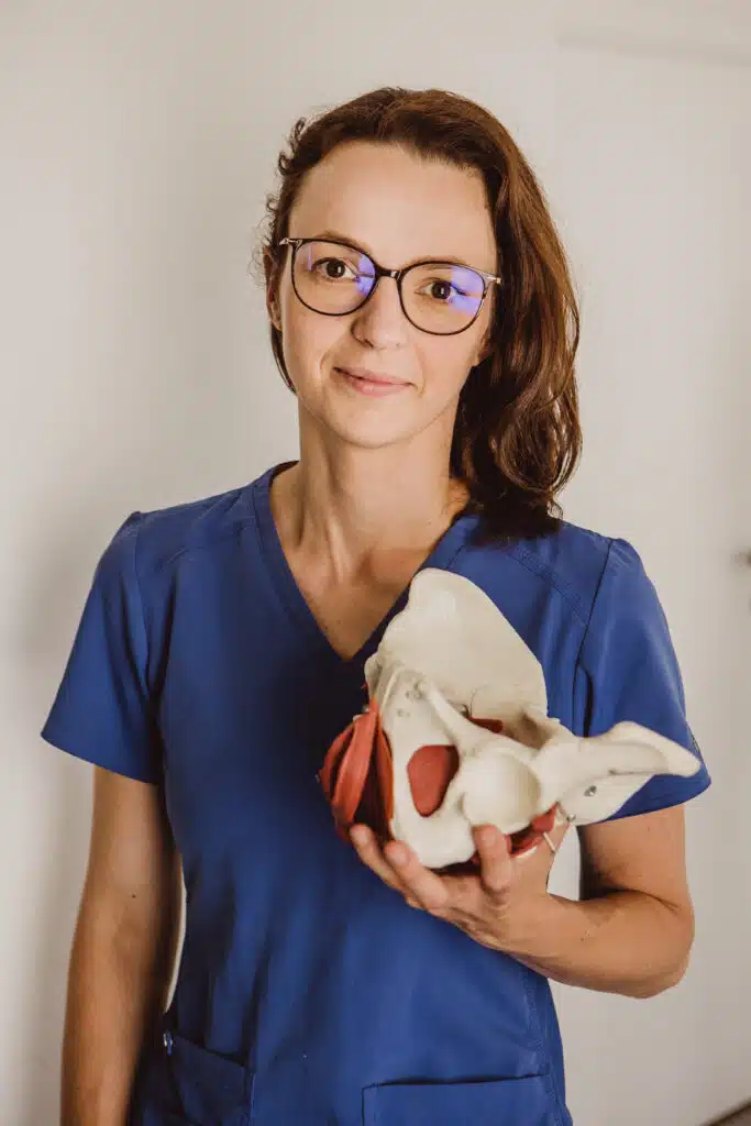 Zdjęcie przedstawiające kobietę trzymającą model miednicy. Jest to fizjoterapeutka Magdalena Kutzner